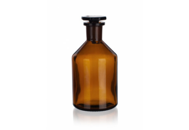 A brown, square-shaped glass bottle with rounded shoulders and a sealed black cap, typically used for storing chemicals or pharmaceuticals. The bottle is positioned on a white background.