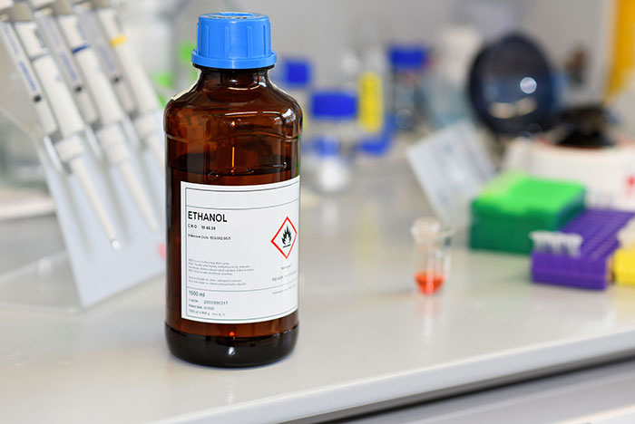 The image of glassware and laboratory equipment in the laboratory environment, with amber glass containing ethanol on it