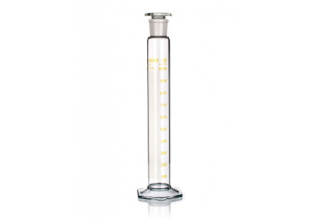 A clear glass graduated cylinder with measurement markings in milliliters (mL) in yellow. The cylindrical vessel is used for measuring the volume of liquids and has a stopper at the top and a hexagonal base for stability.